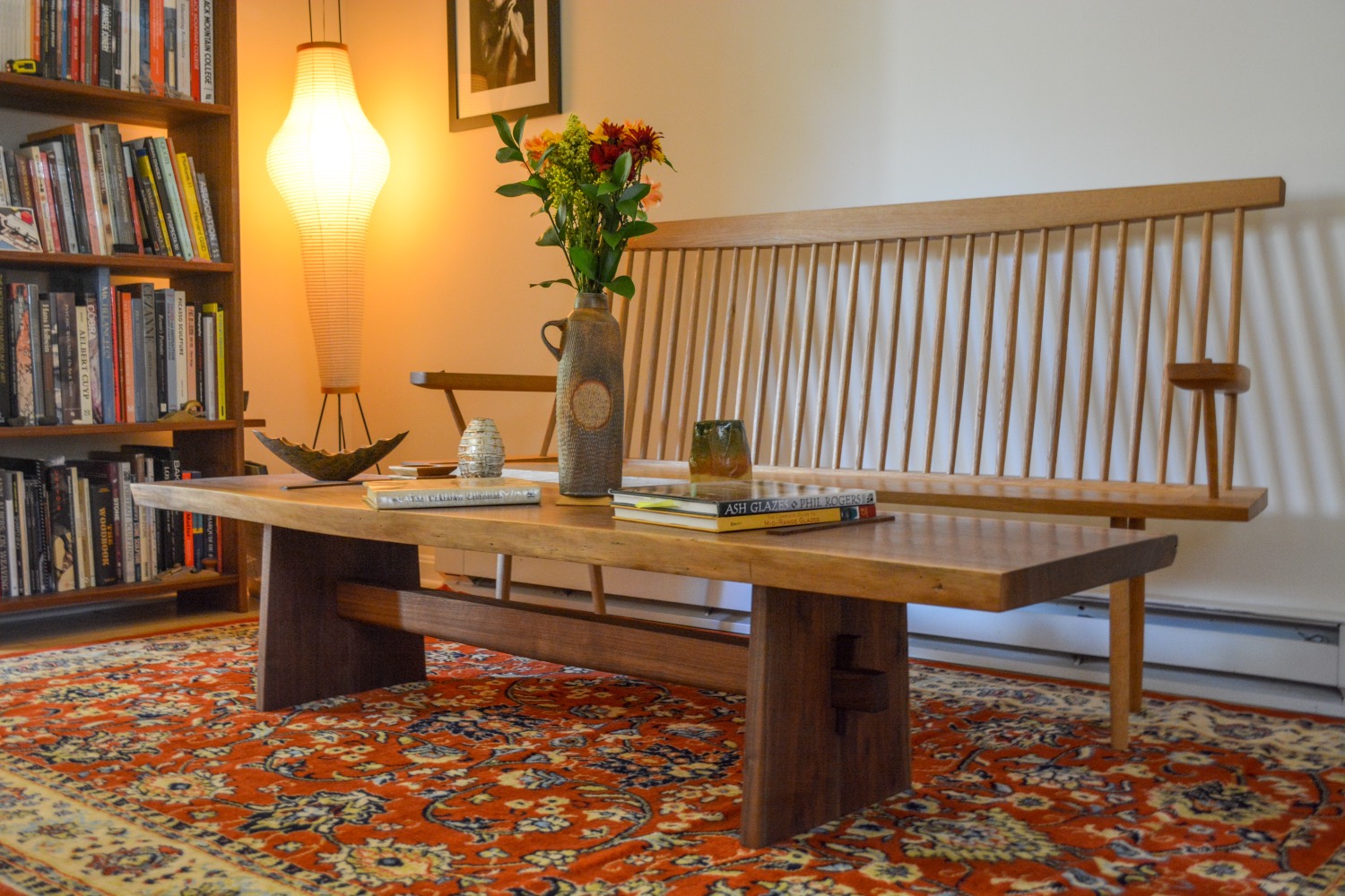 Panel trestle coffee table with a live-edge top, in a book-lined room
