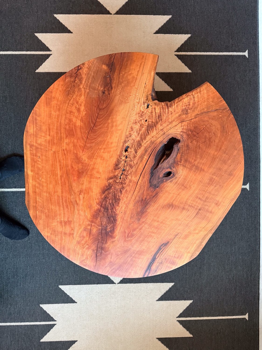 Looking down on a round live-edge walnut coffee table top, grain and live edge catching the light