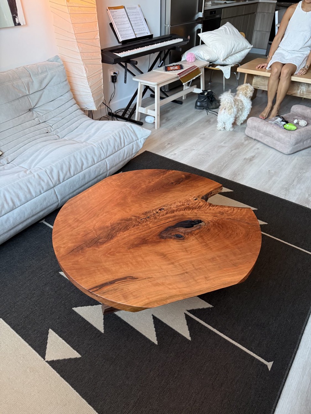 Round live-edge coffee table on two outward-splayed trestle legs