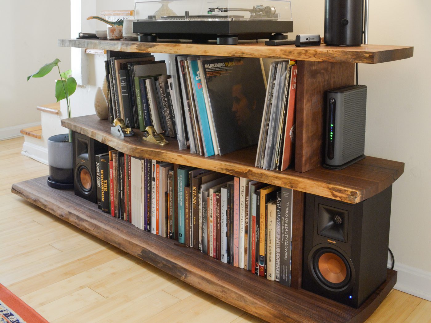 A three-tier live-edge walnut console with a turntable and ceramics on top and vinyl records filed upright below